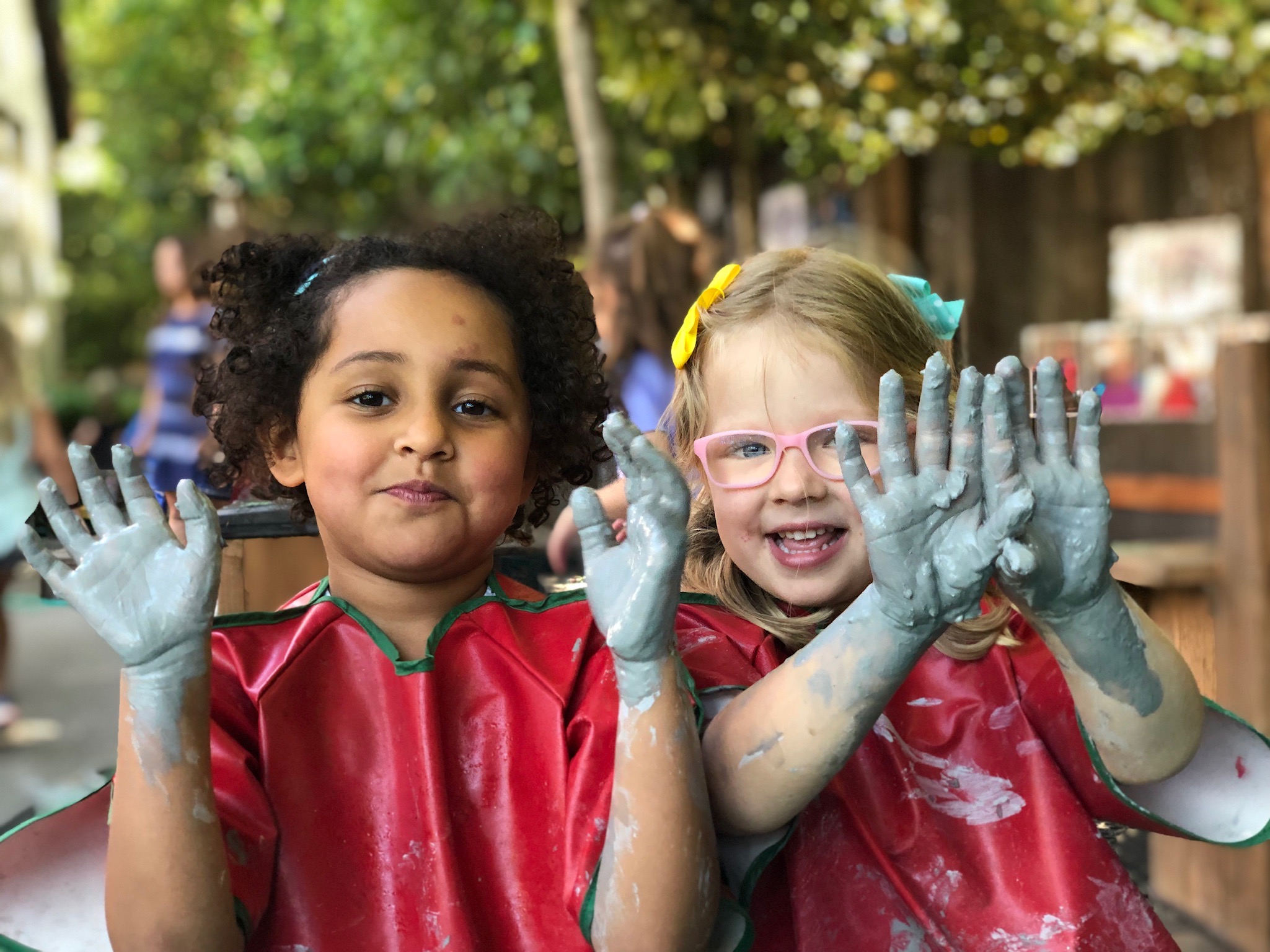 Two children proudly showing their painted hands at The Ross Preschool