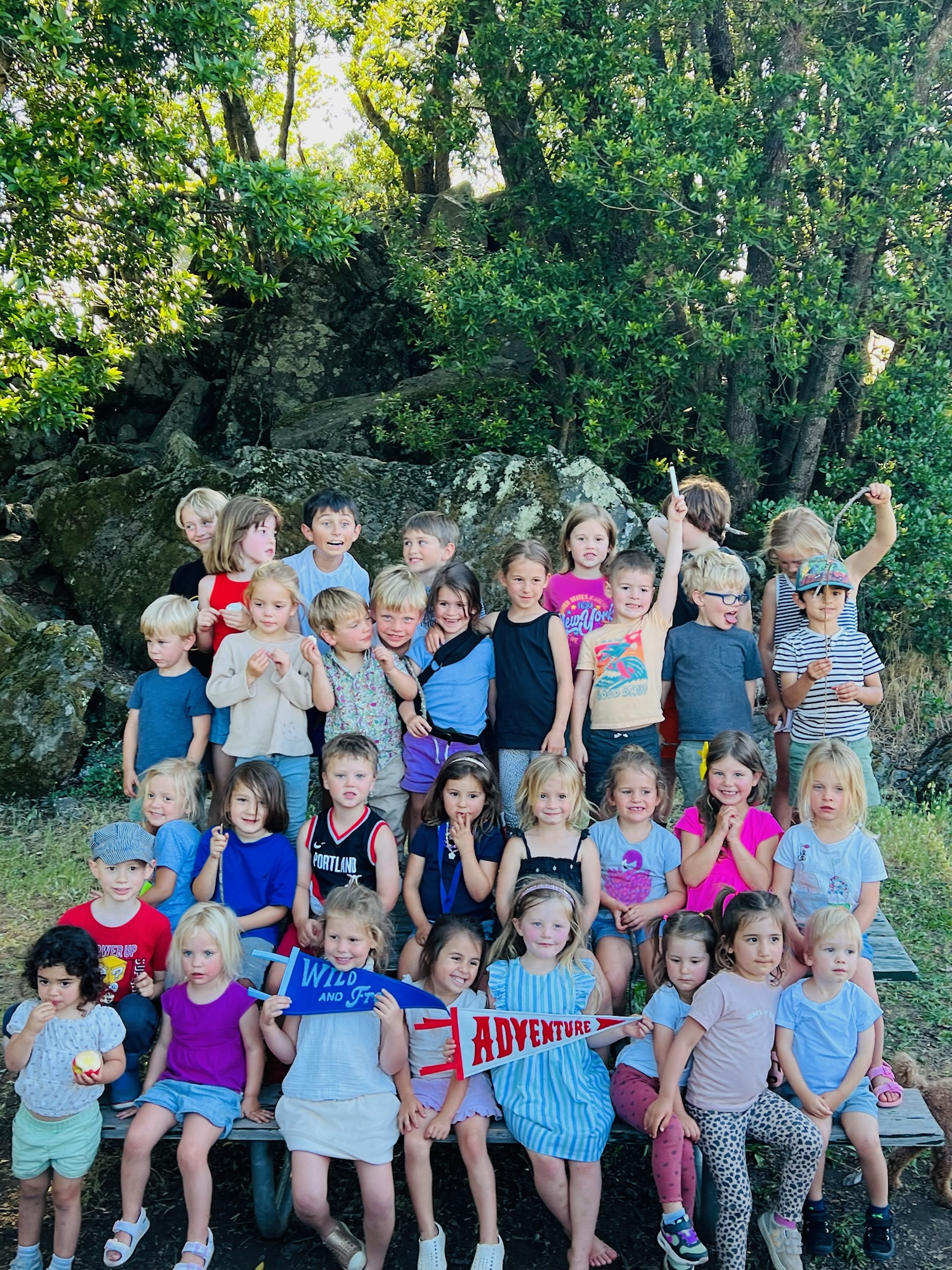 Multi-age TRP children celebrating outdoors with Adventure pennant